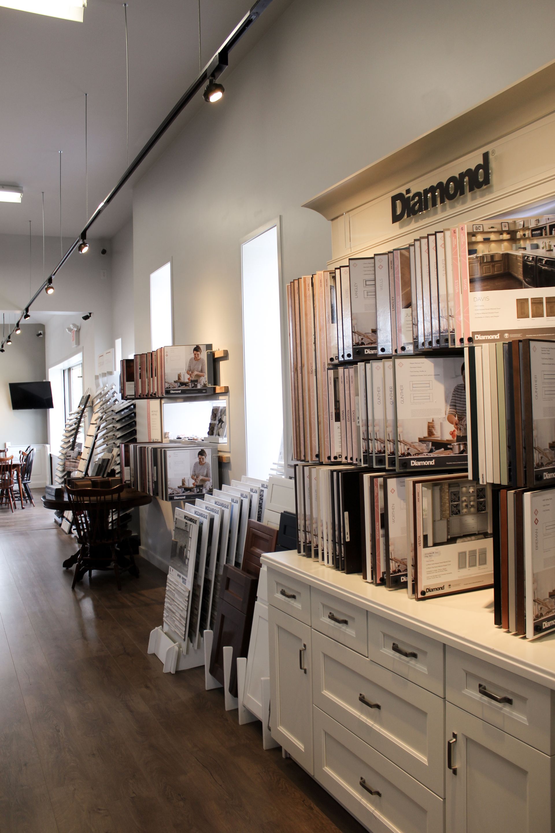 Bright retail showroom with wall-mounted curtain and fabric displays and white cabinets on hardwood floors