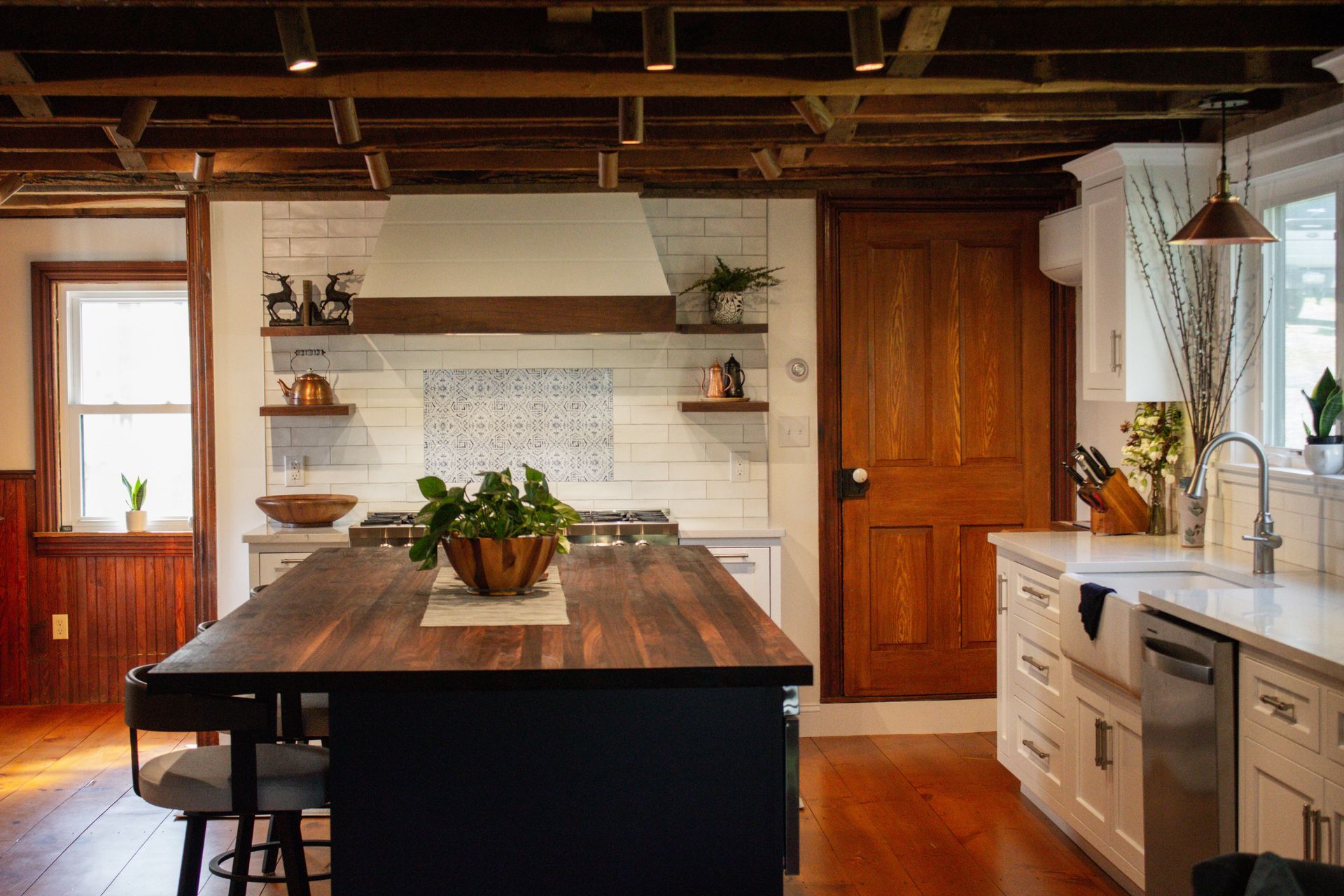 Rustic kitchen with wood island, white cabinets, farmhouse sink, and exposed ceiling beams