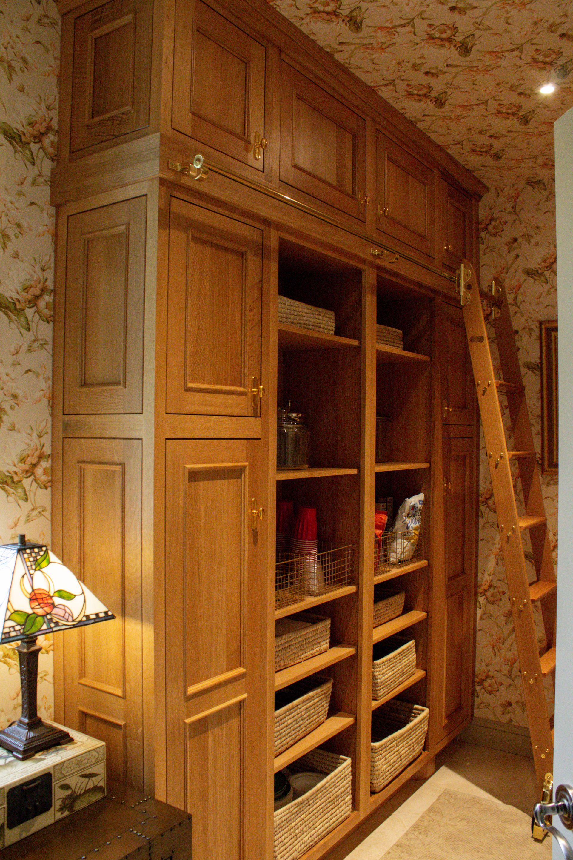 Tall wooden built-in cabinet with shelves in a cozy floral-wallpapered room