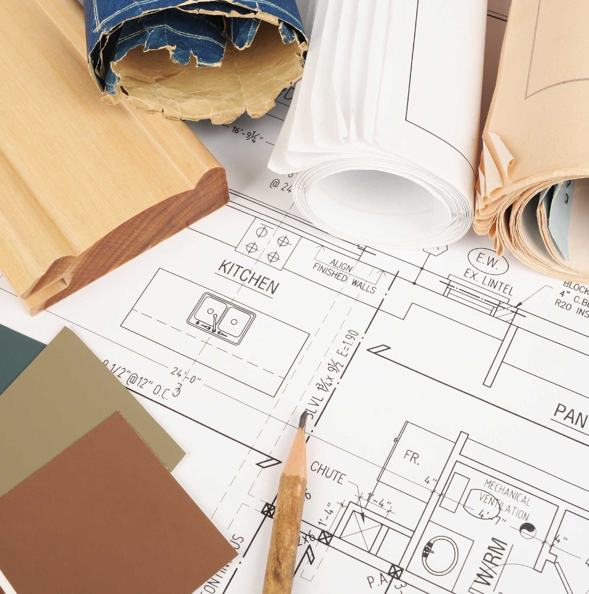 Rolled paint samples and a pencil over house floor plans on a table
