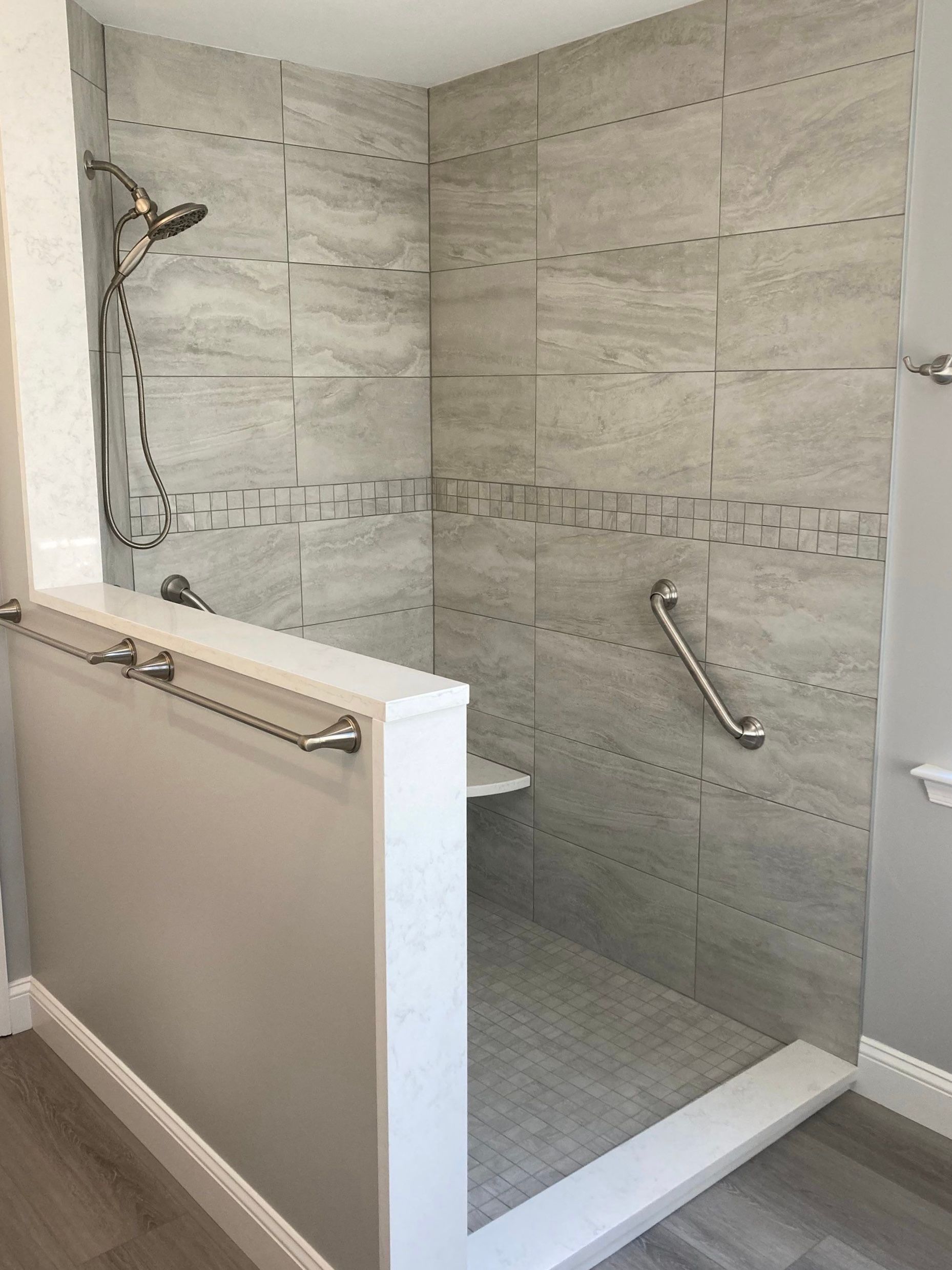 Accessible walk-in shower with tiled walls, grab bars, and a low entry curb in a bathroom