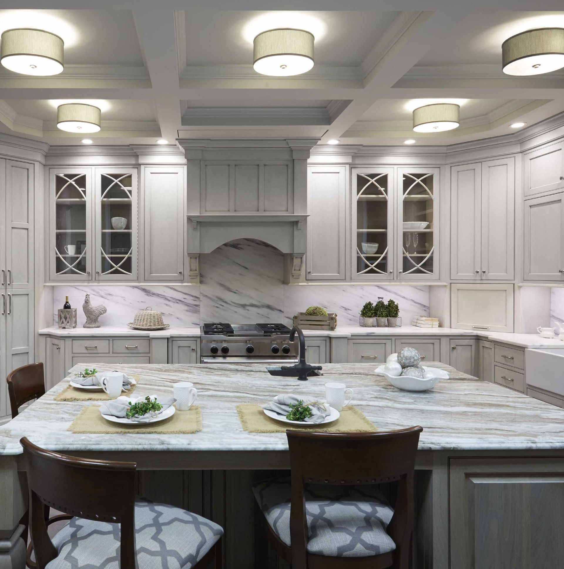 Bright white luxury kitchen with marble island, bar stools, and glass-front cabinets