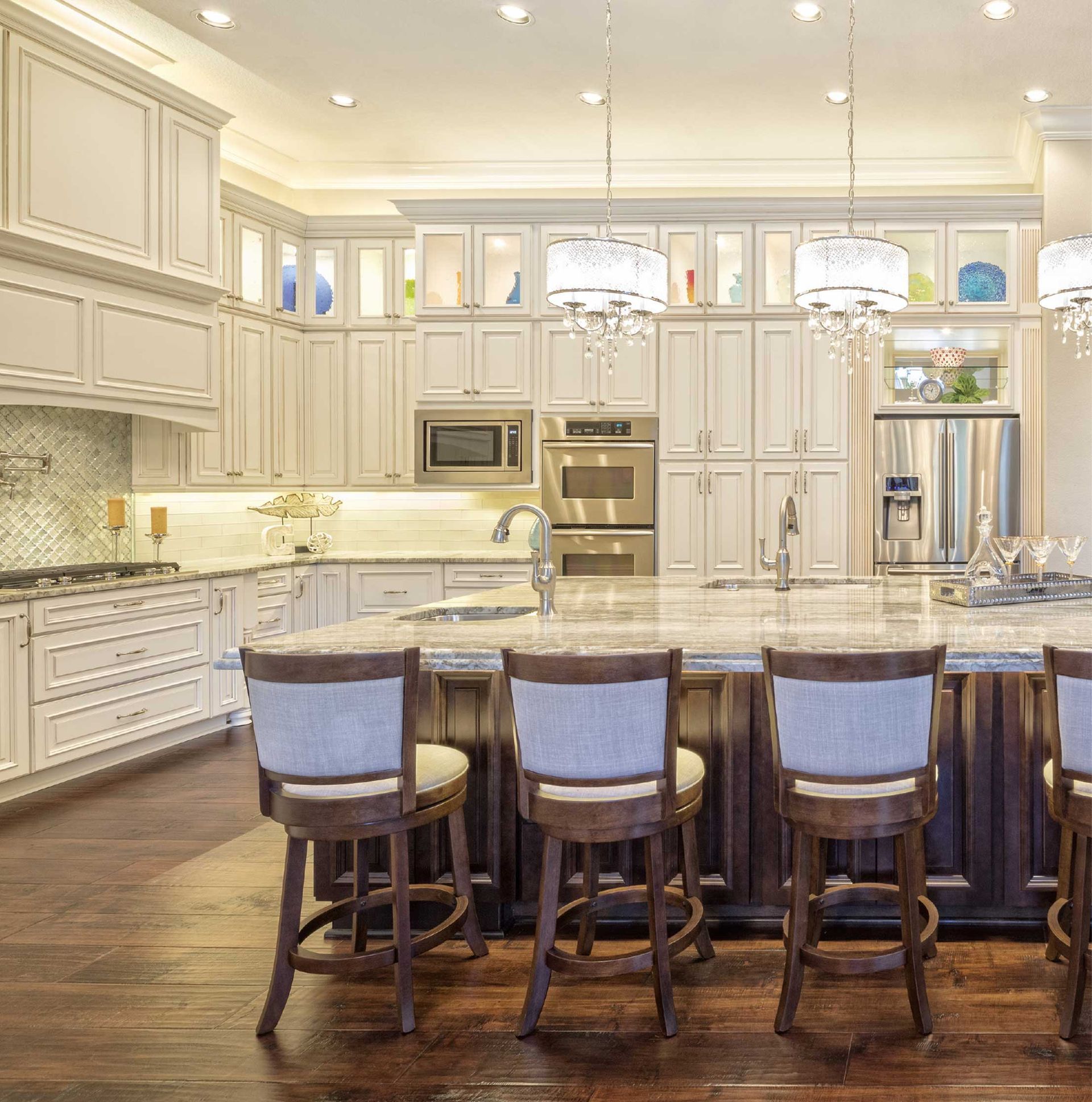 Elegant white kitchen with marble island, dark wood stools, and stainless steel appliances