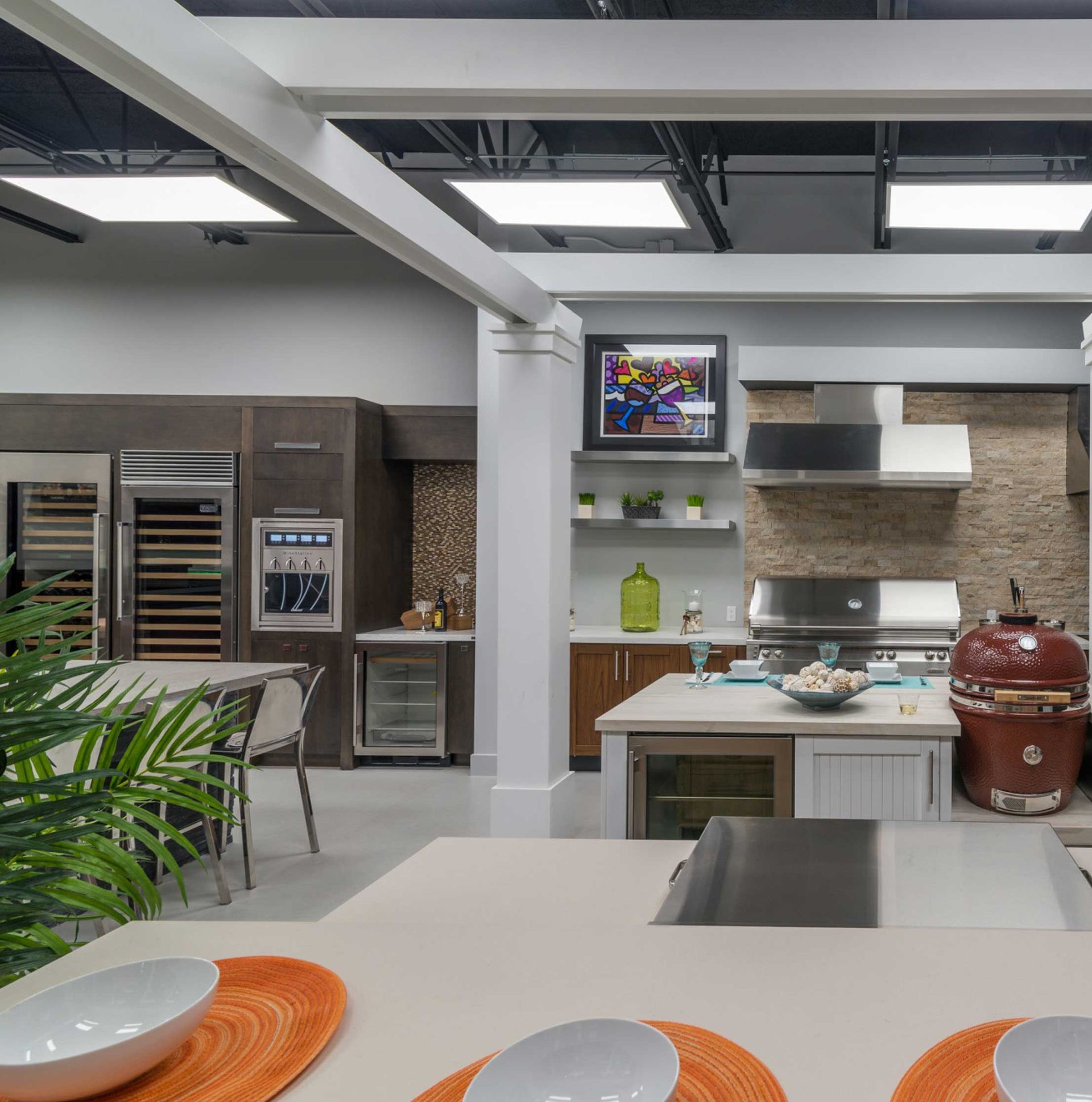 Modern kitchen with island, stainless steel appliances, gray cabinets, and a green plant in the foreground