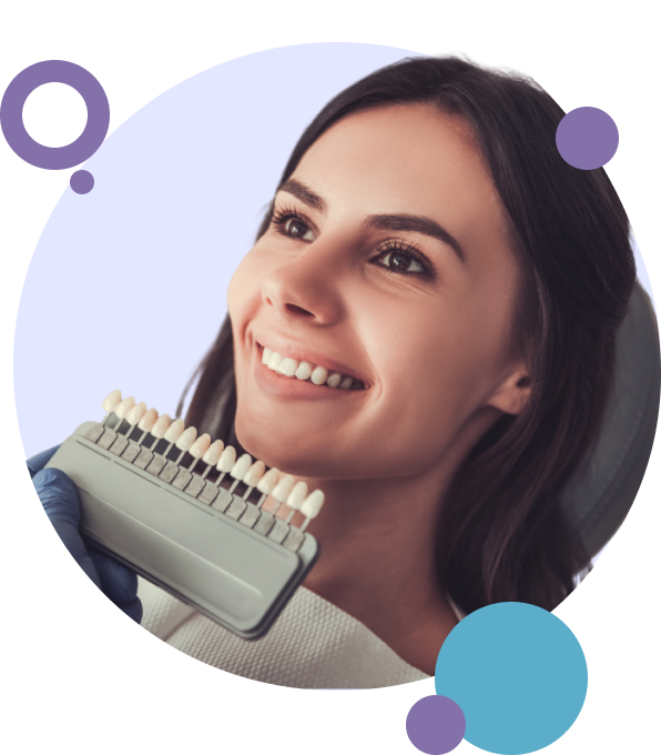 Dentist holding veneer shade guide up to patient's teeth