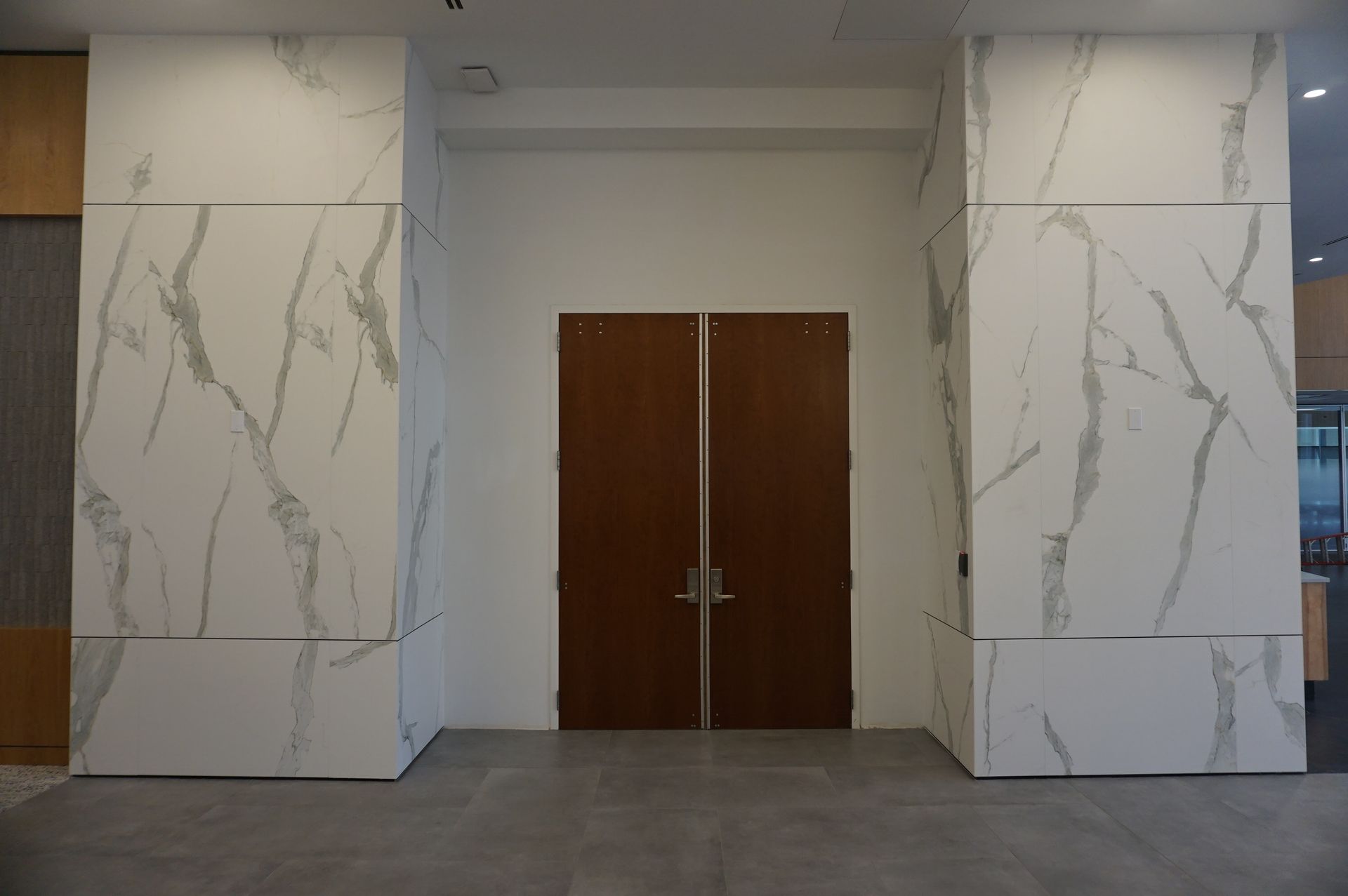 A hallway with marble walls and wooden doors in a building.