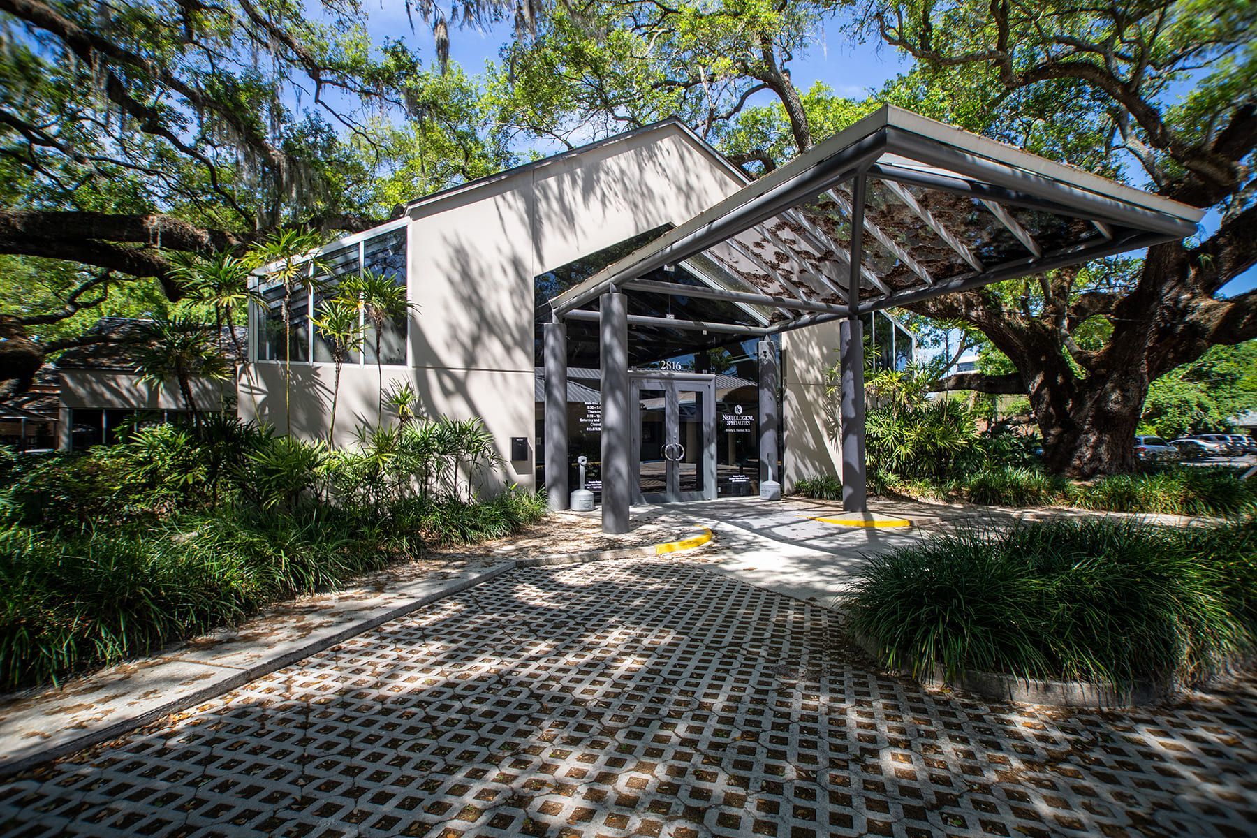 A large white building with a canopy over the entrance surrounded by trees.