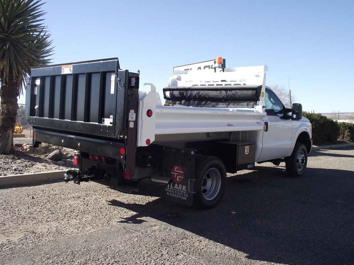 White dump truck parked outdoors with the bed tilted up.