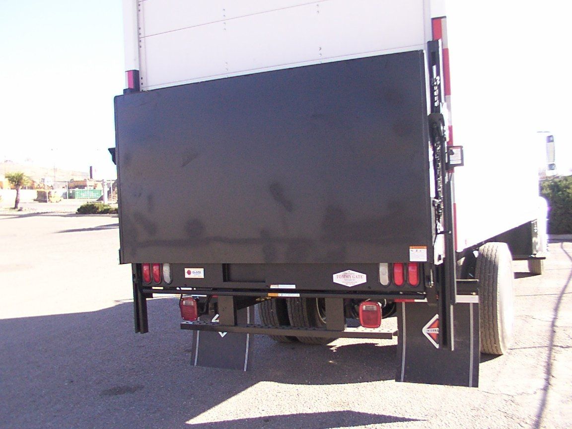 Rear view of a delivery truck with a black lift gate lowered, ready for loading.