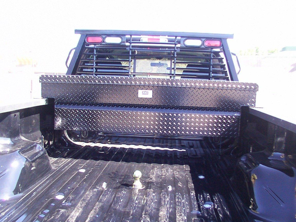 Black truck bed with diamond plate toolbox and headache rack.