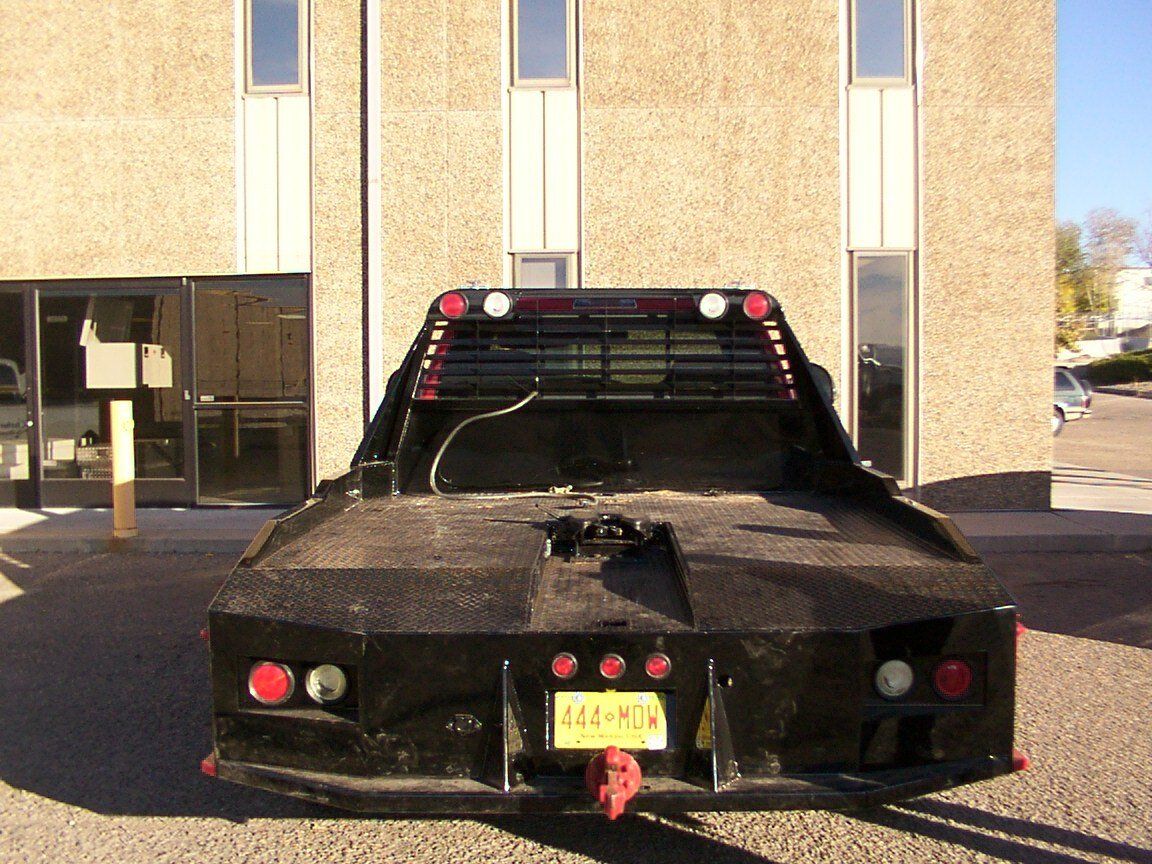Black flatbed truck parked in front of a building with large windows.