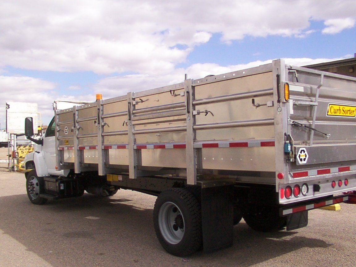 White dump truck with an aluminum bed, parked on pavement.