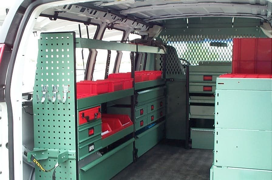 Inside of a green work van with shelves, drawers, and storage bins. Red bins inside.