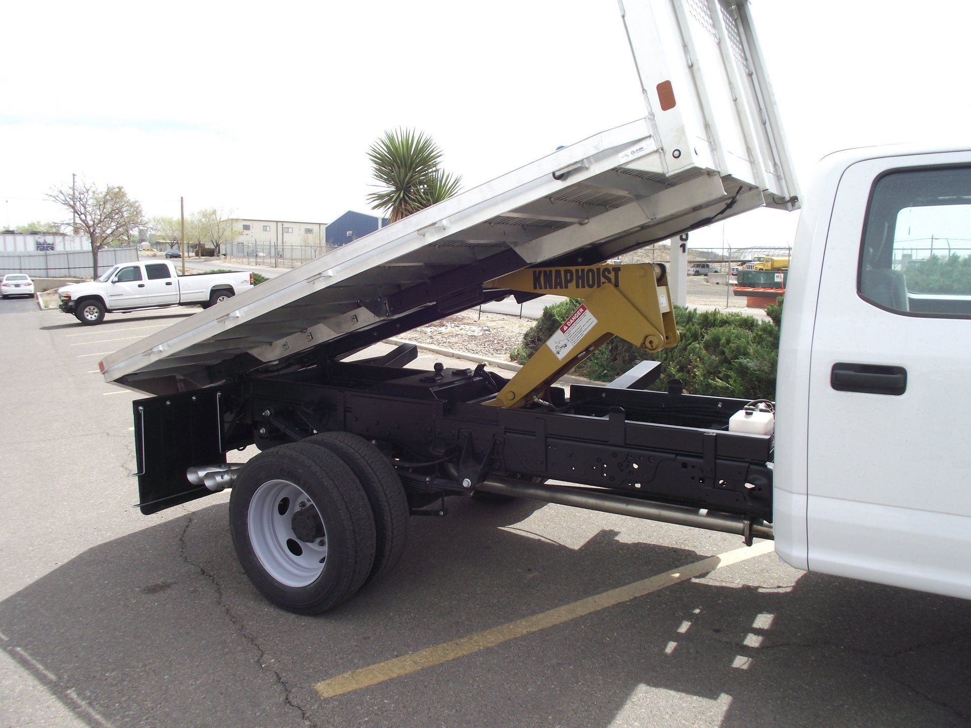 White pickup truck with bed raised, revealing hydraulic lift.