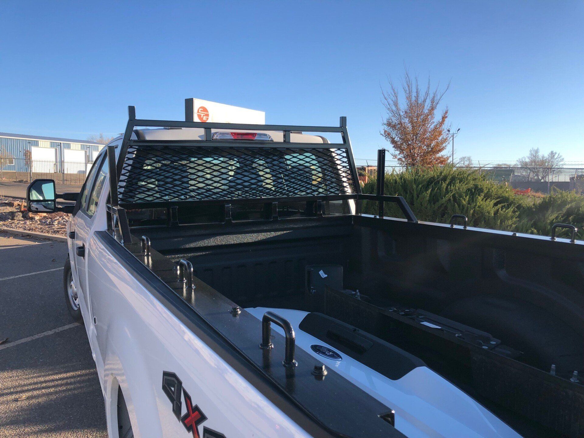 White pickup truck bed with a black ladder rack and mesh screen.