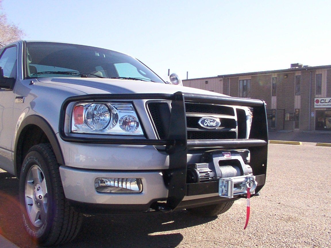 Silver Ford pickup truck with a black front guard, winch, and a red tow rope in a parking lot.