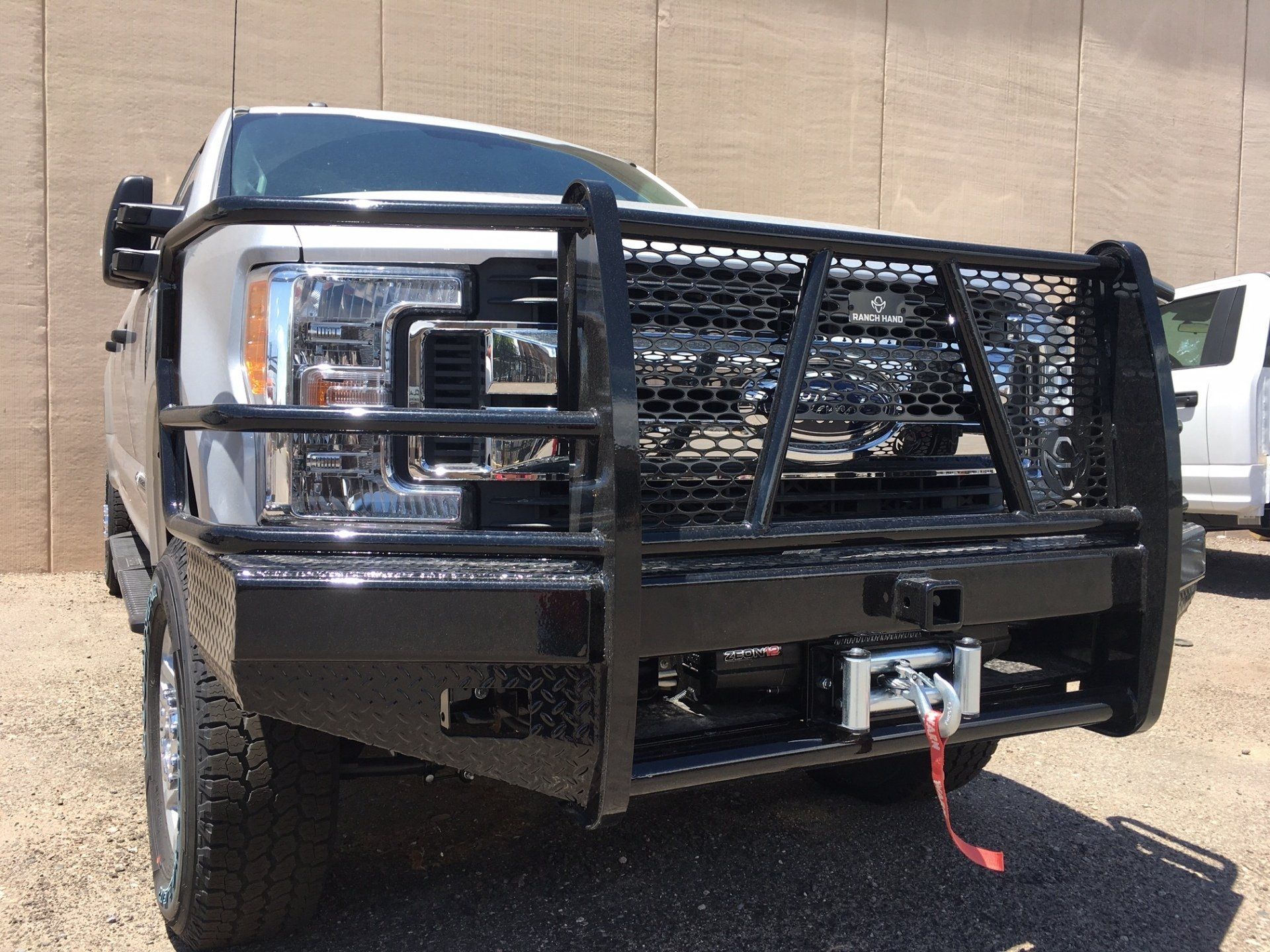 White truck with black grill guard and winch on front bumper.