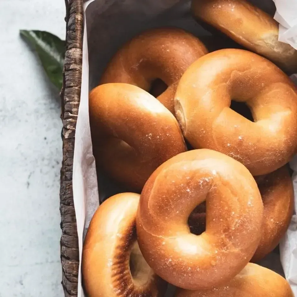Glazed doughnuts in a box, with golden-brown rings stacked closely together.