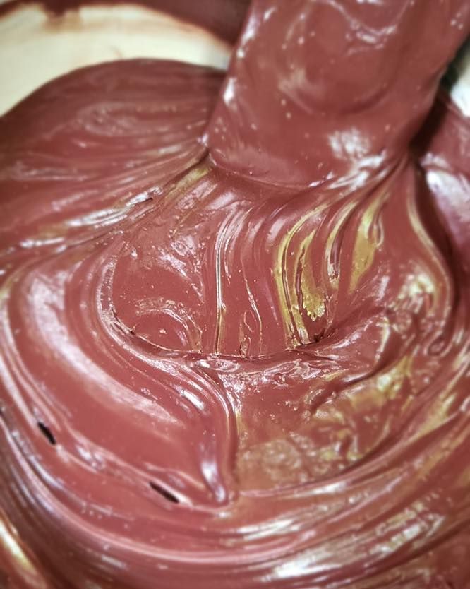 Close-up of glossy red-brown swirled material with yellow streaks and a raised central fold