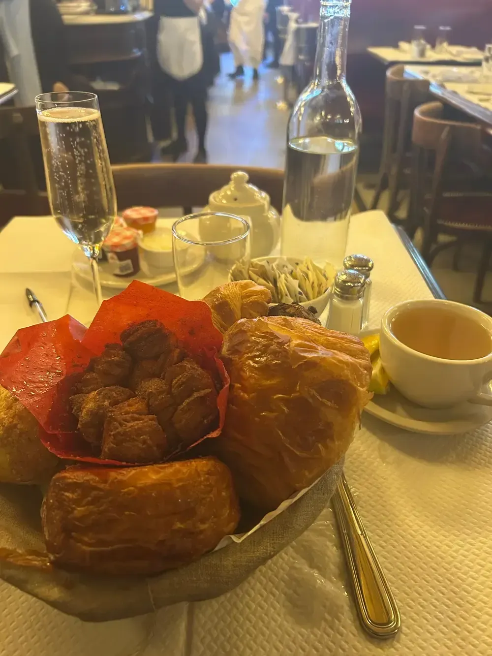 Breakfast table with pastries, strawberries, coffee, water, and a glass of orange juice in a café