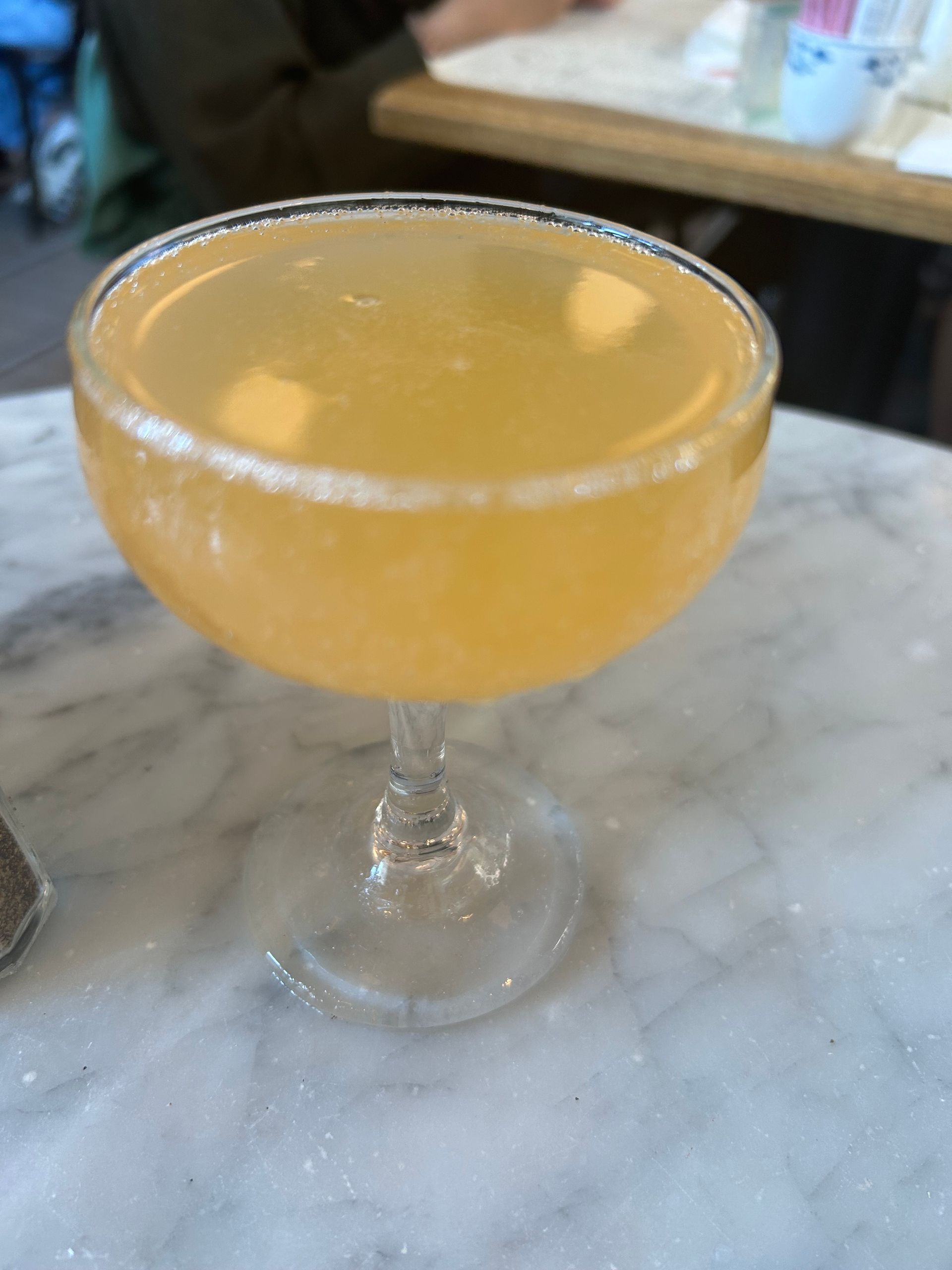 Orange cocktail in a coupe glass on a marble tabletop