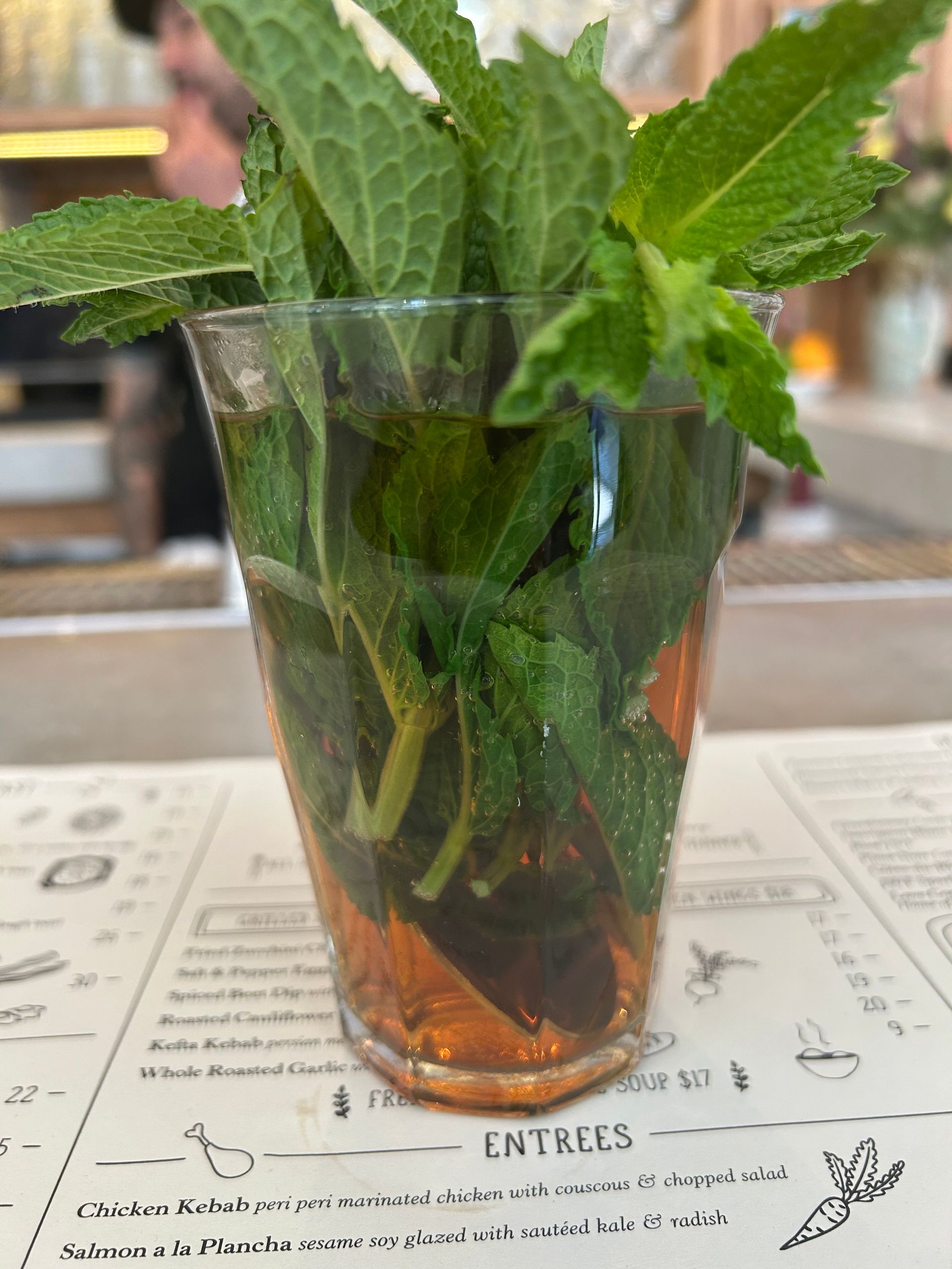 Mint sprigs in a clear glass of iced water on a restaurant table