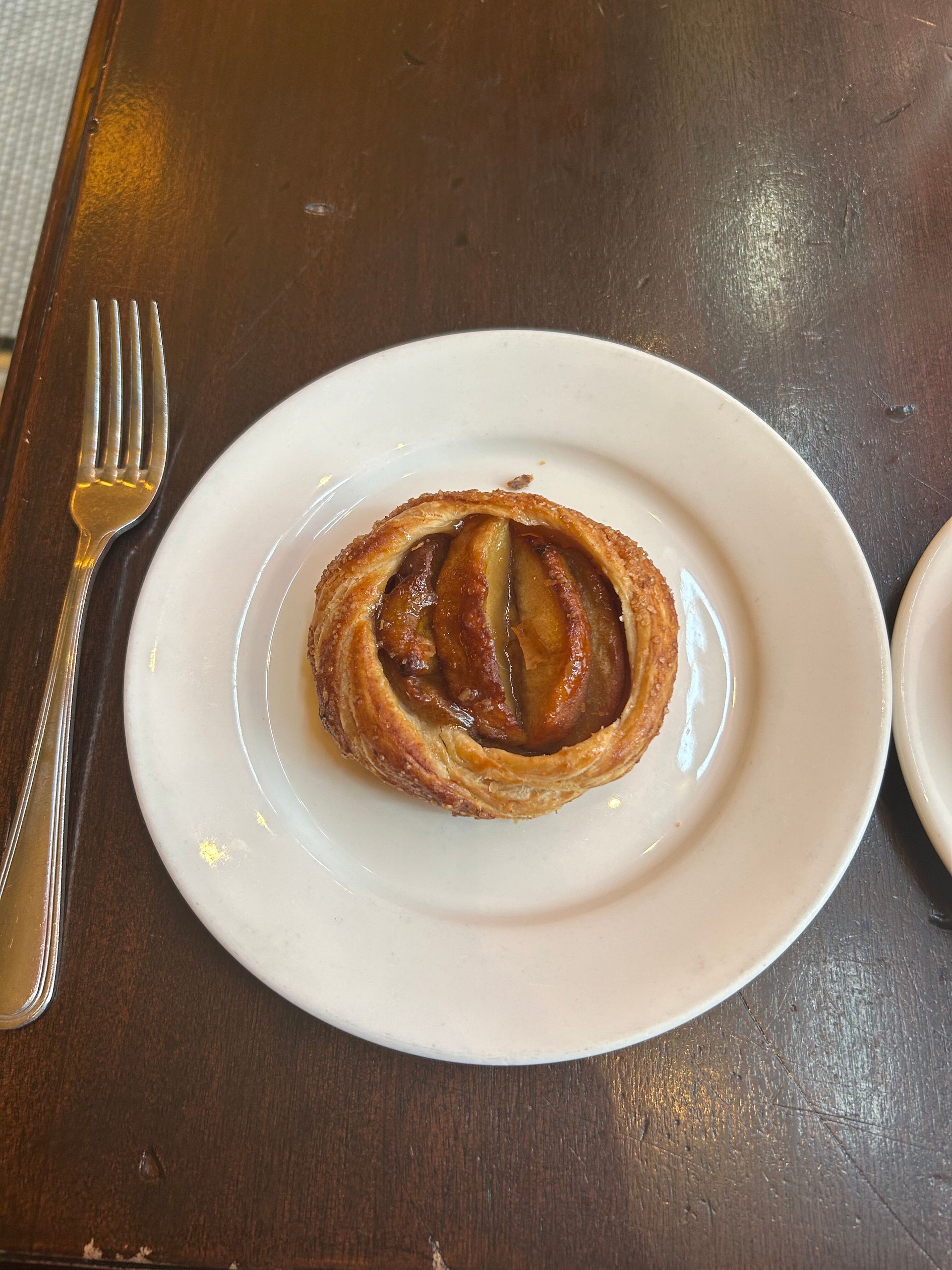 Pastry on a white plate with a fork on a dark table