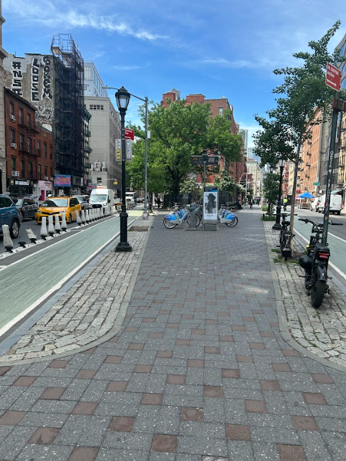 Brick-paved city street with lampposts, parked bikes, and historic buildings under a blue sky