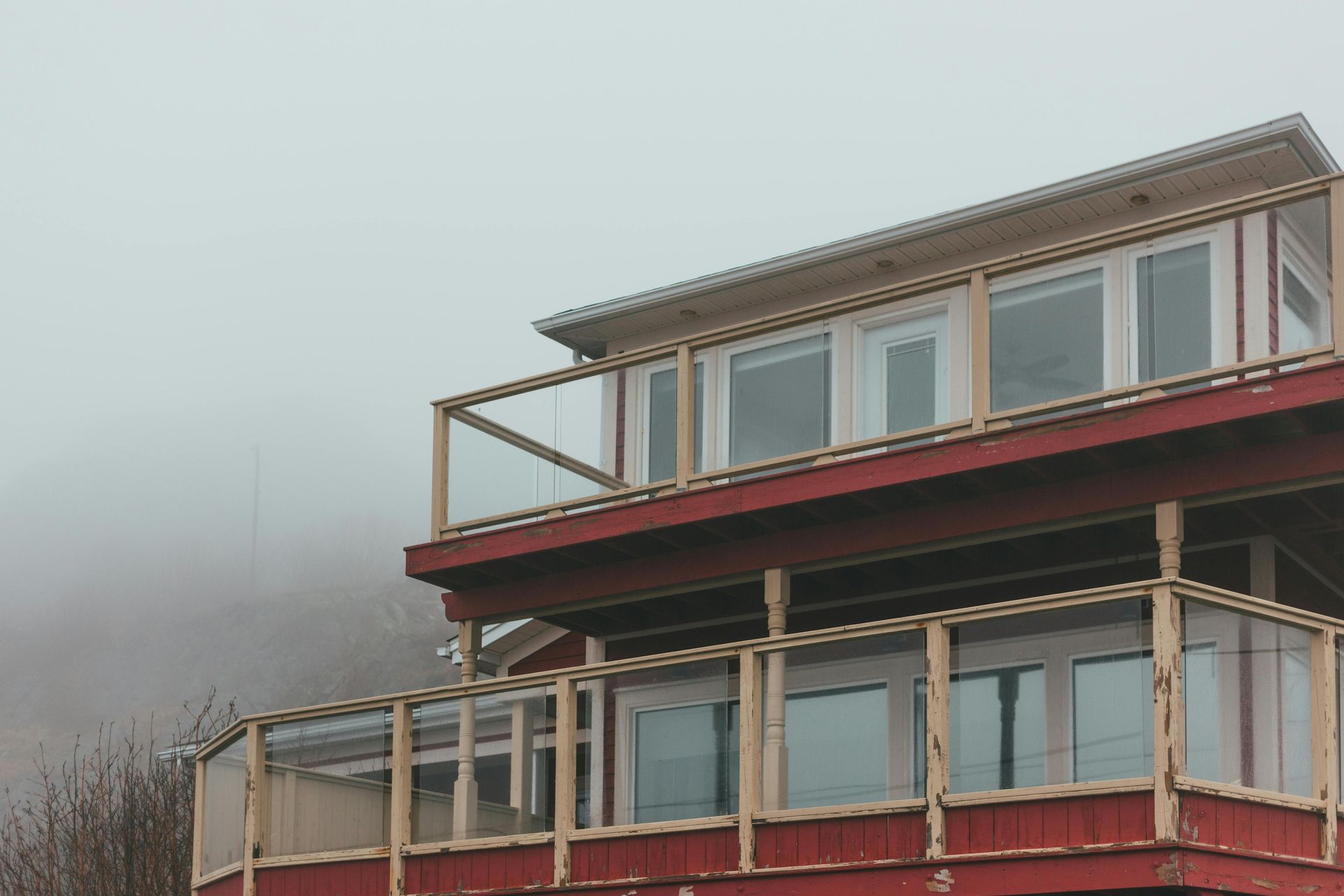 Foggy view of a red and white house with large windows and a balcony