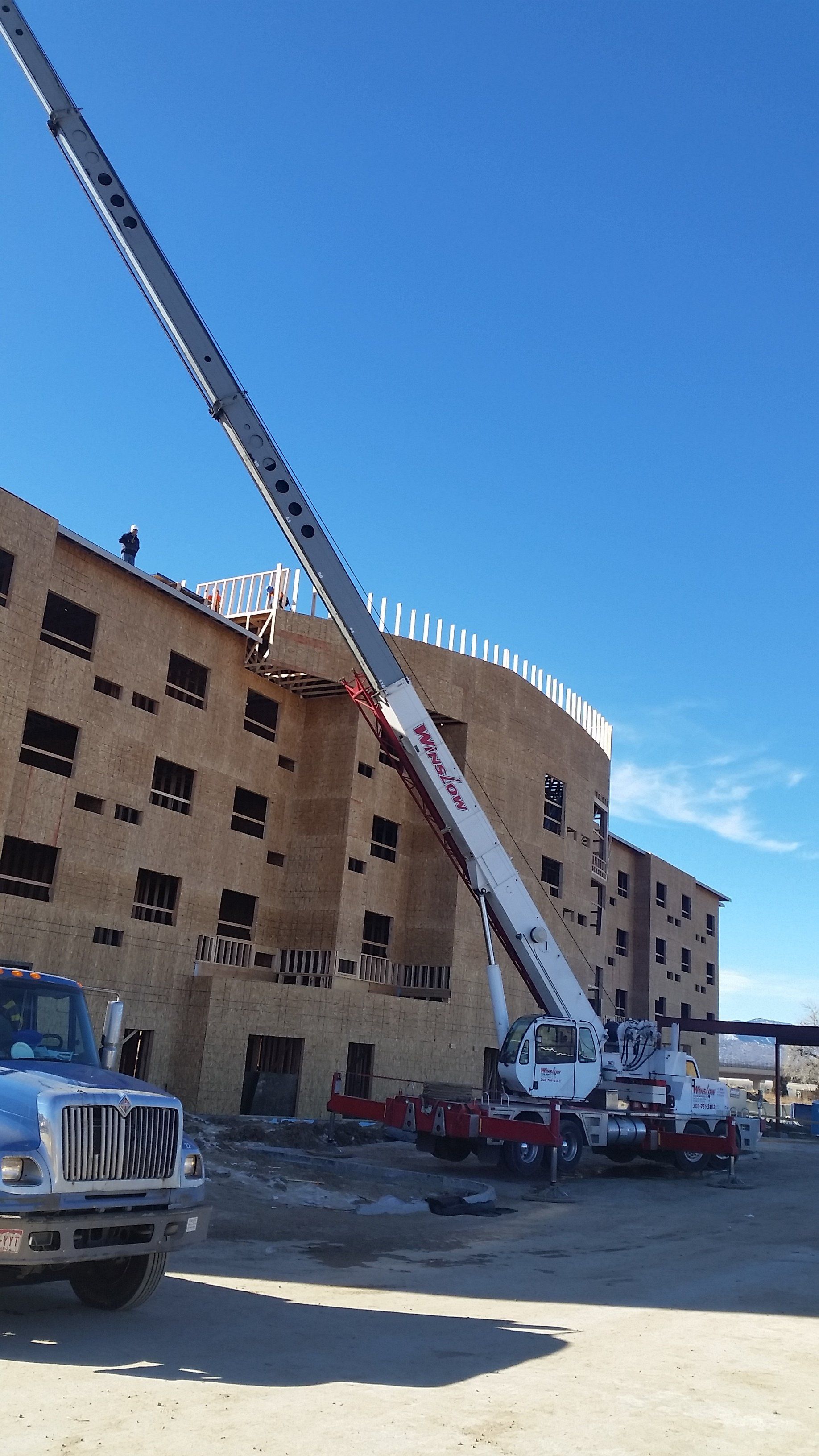 a truck with a crane attached to it is parked in front of a building