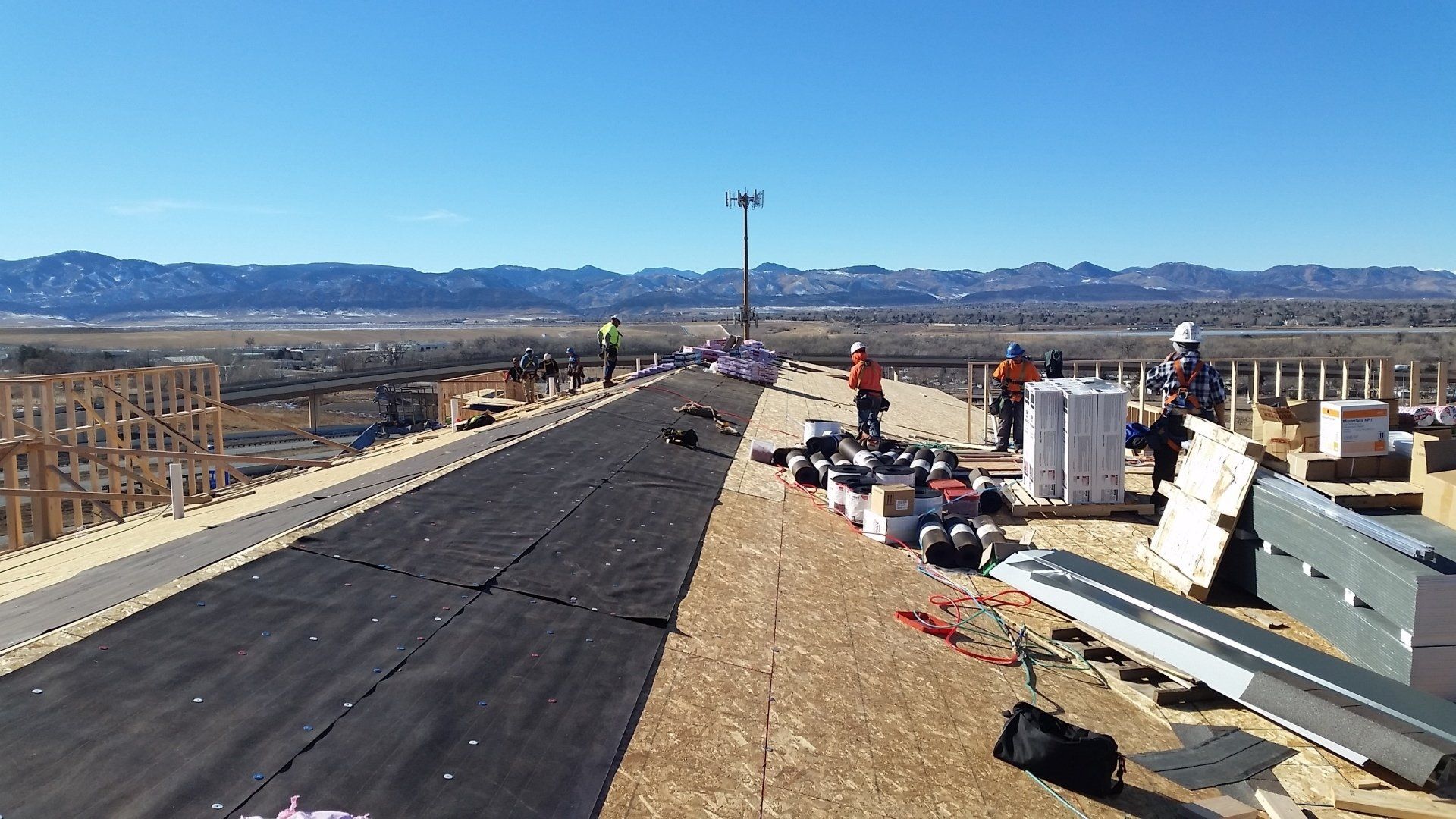 a group of construction workers are working on the roof of a building .