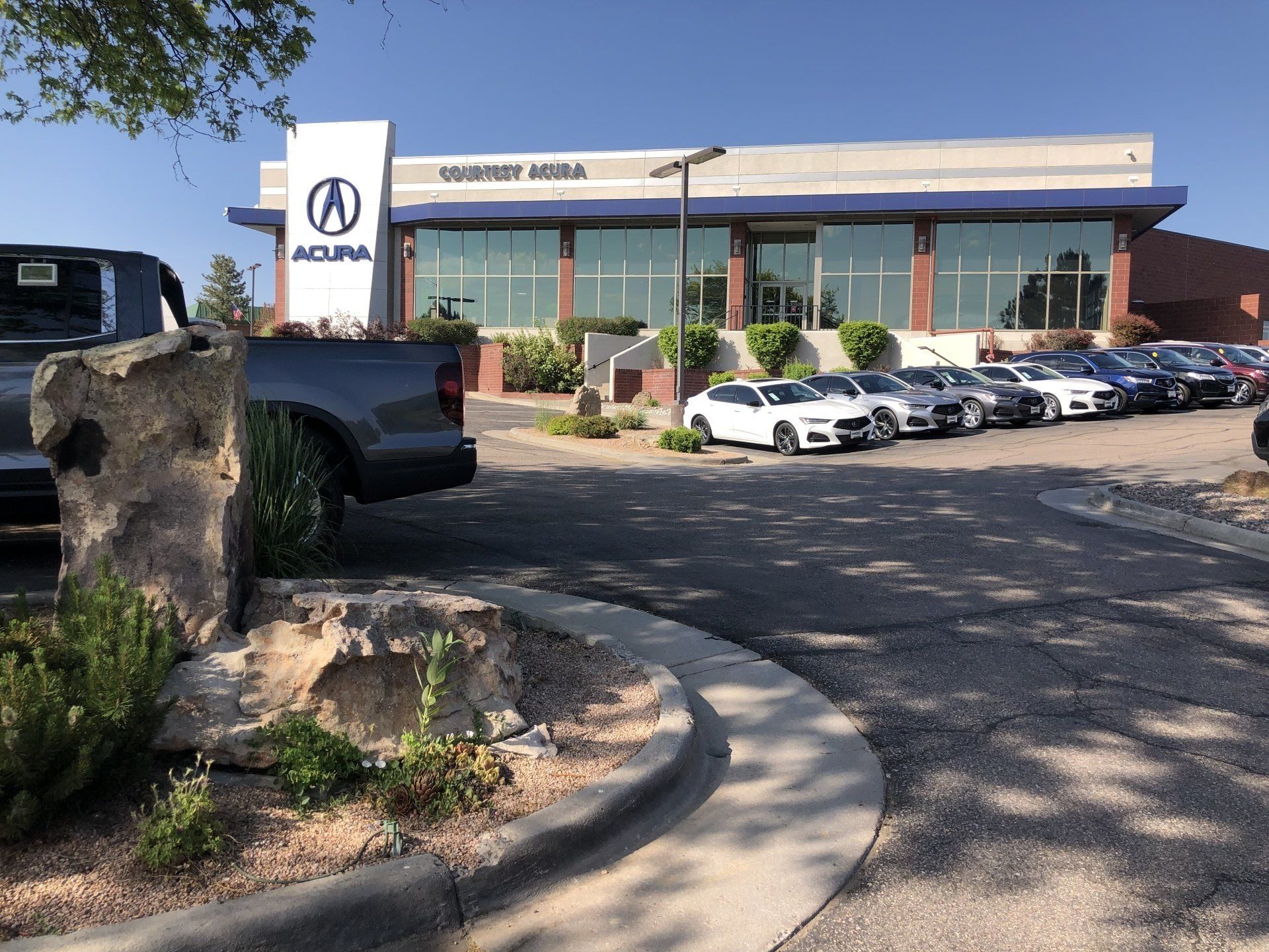 an Acura dealership building with a row of cars parked in front.
