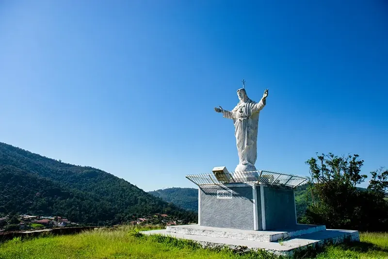 Vista aérea de uma pessoa flutuando em uma piscina natural de cor turquesa brilhante, cercada por vegetação tropical exuberante.