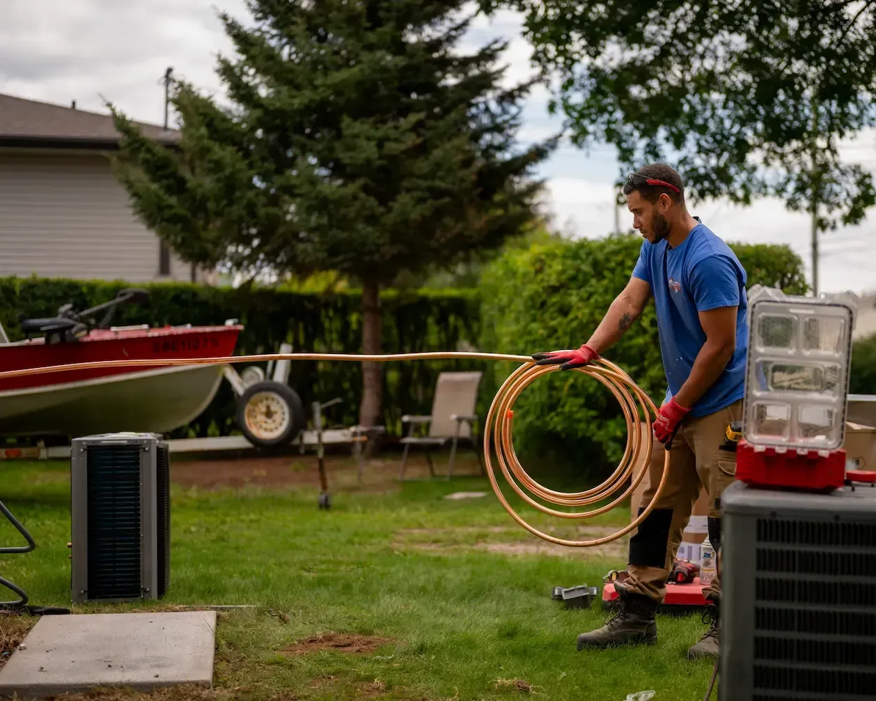 D Peppard Technician unfolding copper tubing for a new air conditioner installation.