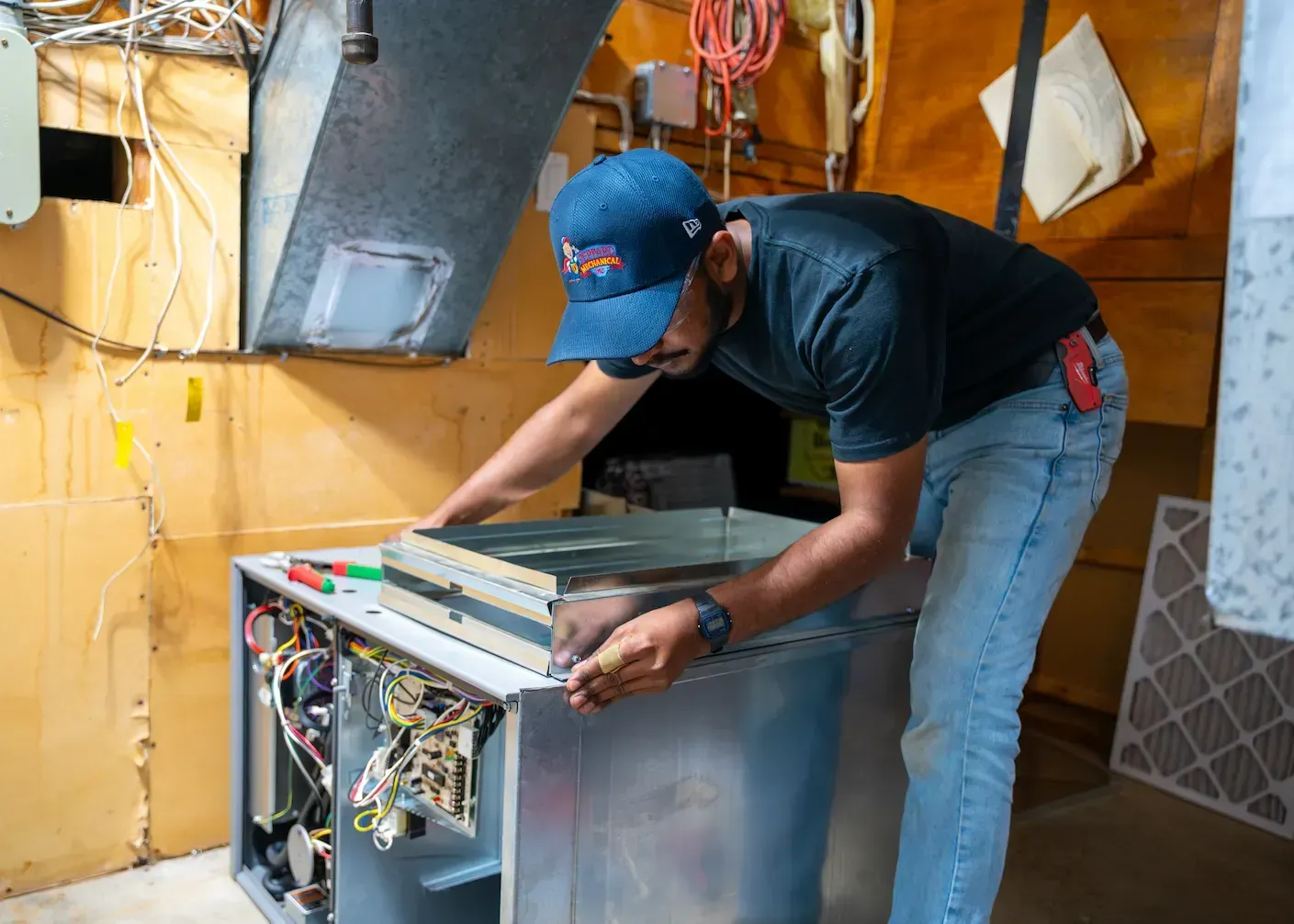 Technician installing a dishwasher in a kitchen, leaning over the open appliance