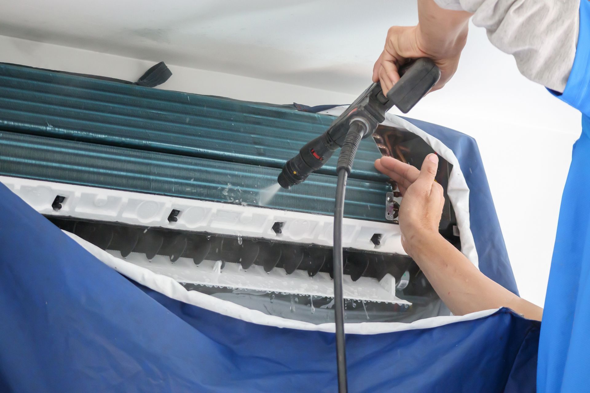 Technician using a heat gun on a blue roof tarp during repairs