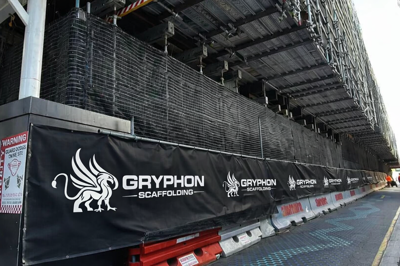 Construction site with scaffolding, safety netting, and a Hutchinson Builders banner.