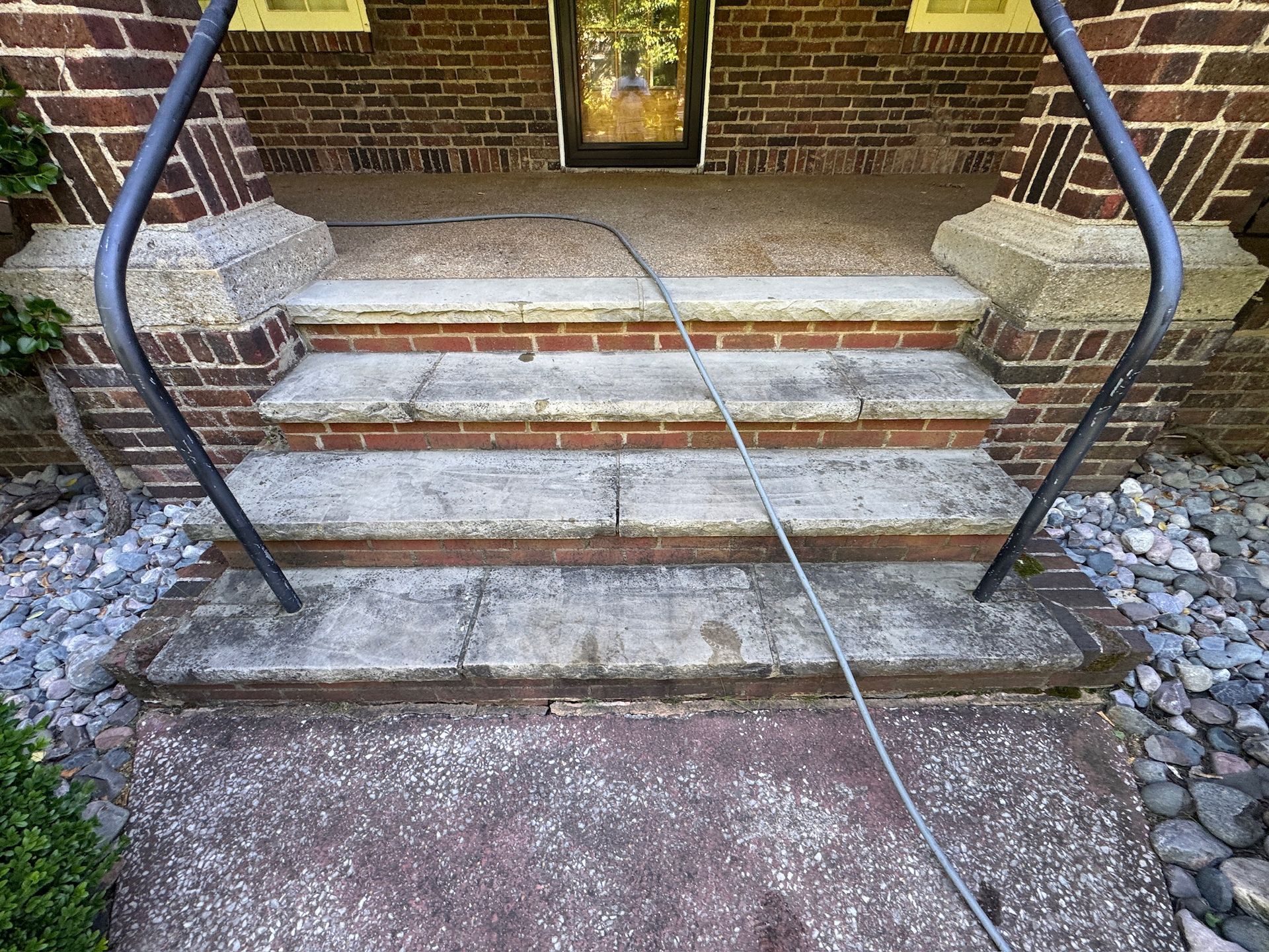 Brick front steps with black railings and a cable stretched across the walkway to the door