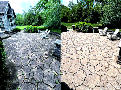 Patio with cracked gray stone on left and tan pavers on right, with white chairs and green hedges surrounding it