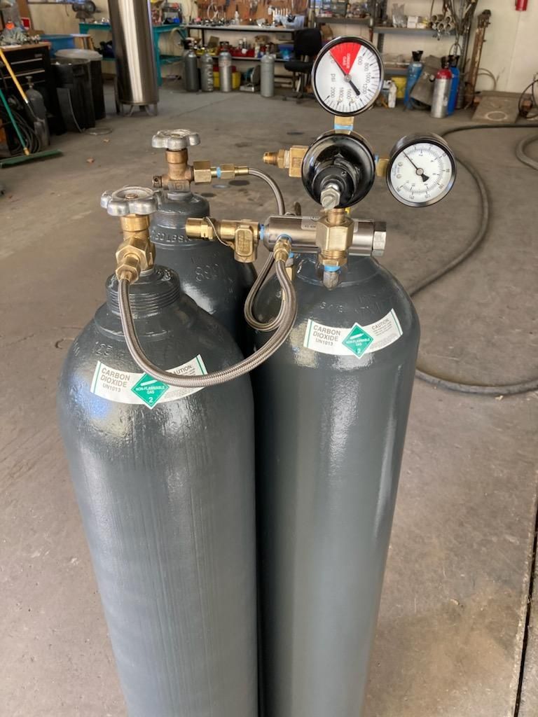 cylinder bottles with valves sitting in warehouse
