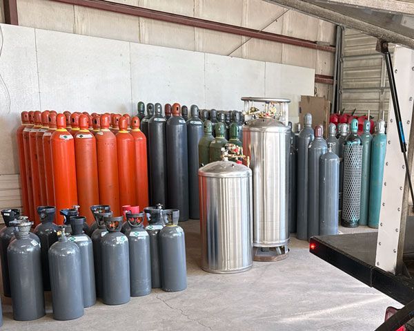 gas cylinders in varying colors lined up in a warehouse