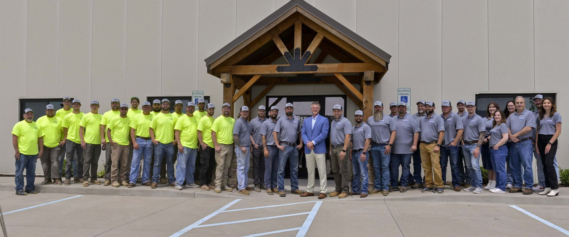 Large group posing outside a building, with workers in neon yellow shirts and others in blue uniforms