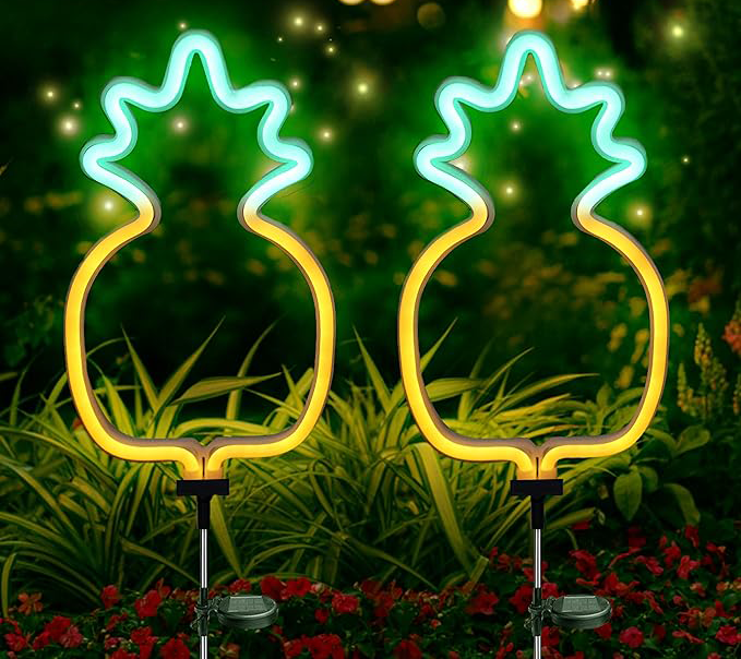 Two glowing neon pineapple lights on garden stakes at night