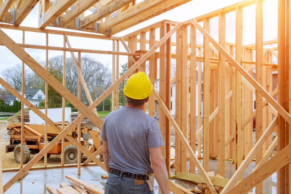 Man Standing In A Wooden Frame Of A House Under Construction — Pro Vision Property Inspections In Merewether, NSW
