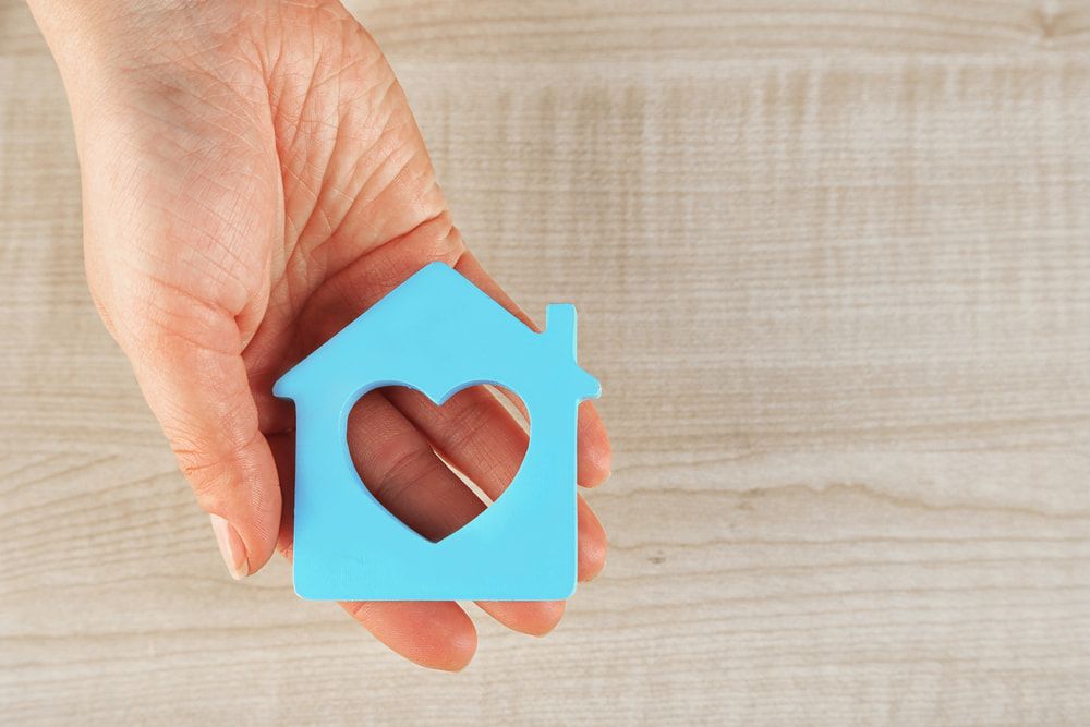 Person Holding A Blue House With A Heart Cut Out Of It — Pro Vision Property Inspections In Lake Macquarie, NSW