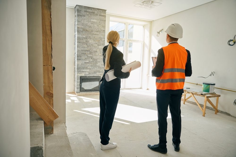 Woman and Man Reviewing Construction Plans in a Room Under Renovation — Pro Vision Property Inspections In Merewether, NSW
