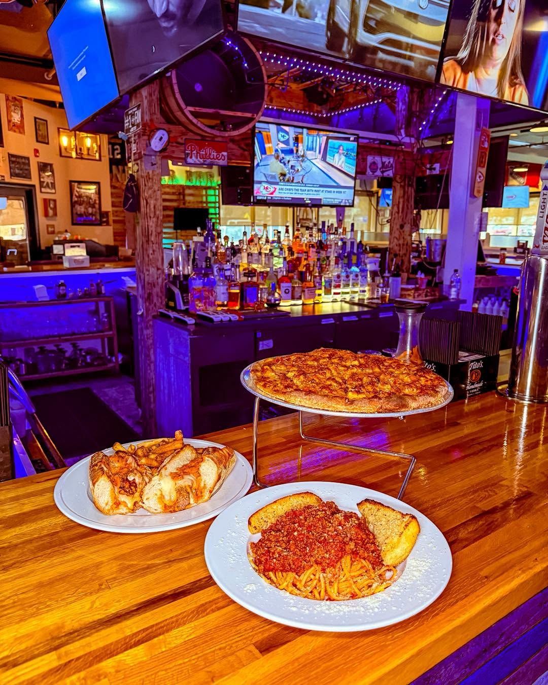 Two slices of pizza on a wooden bar table in a neon-lit sports bar
