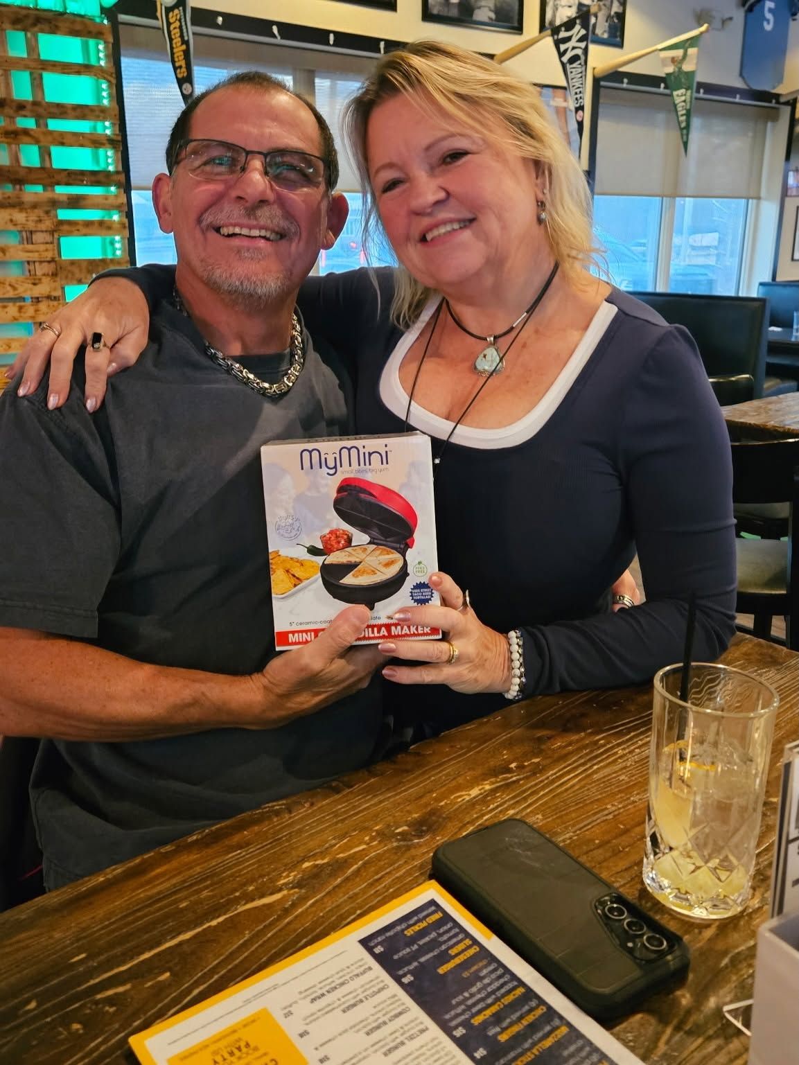 Smiling couple at a restaurant holding a cookbook with a sushi cover