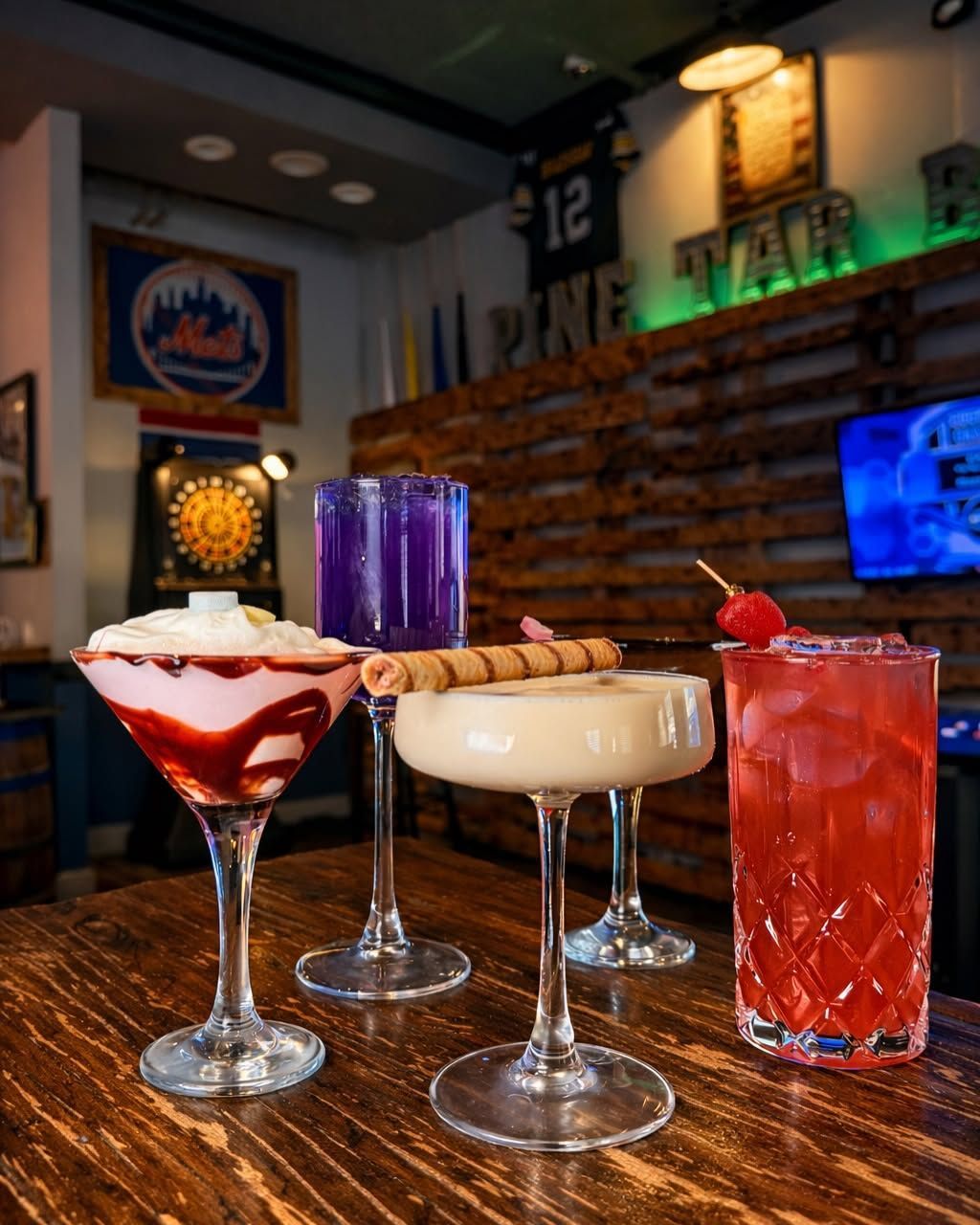 Three colorful cocktails on a bar counter in a dimly lit sports bar