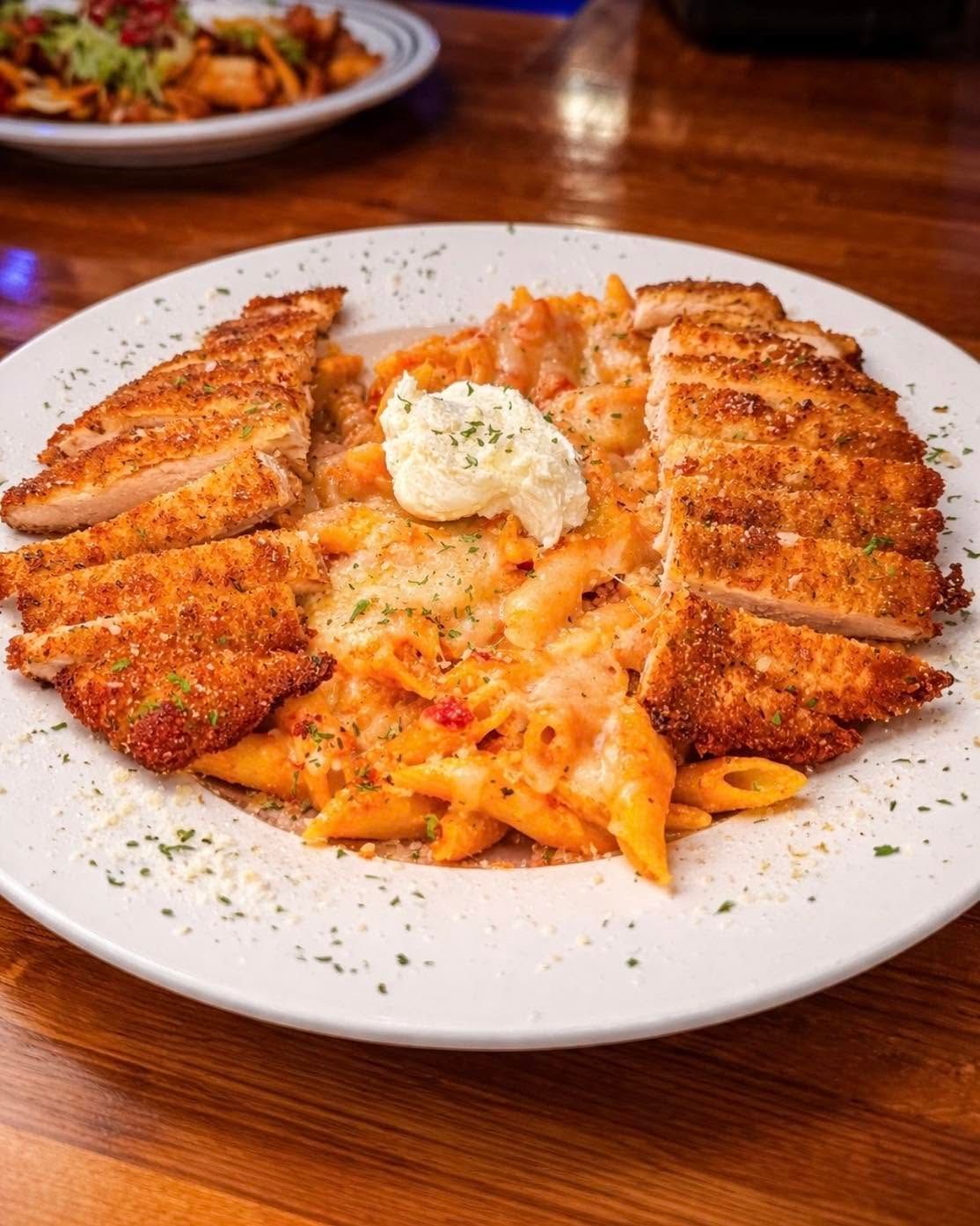 Breaded chicken cutlets with pasta and a dollop of butter on a white plate